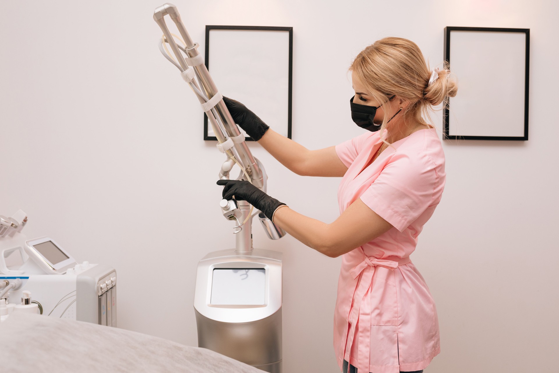 Beautician woman in medical clothes,mask,gloves prepares beauty device laser CO2 fractional. Laser used for skin rejuvenation. Medical cosmetic procedure in beauty laser clinic concept