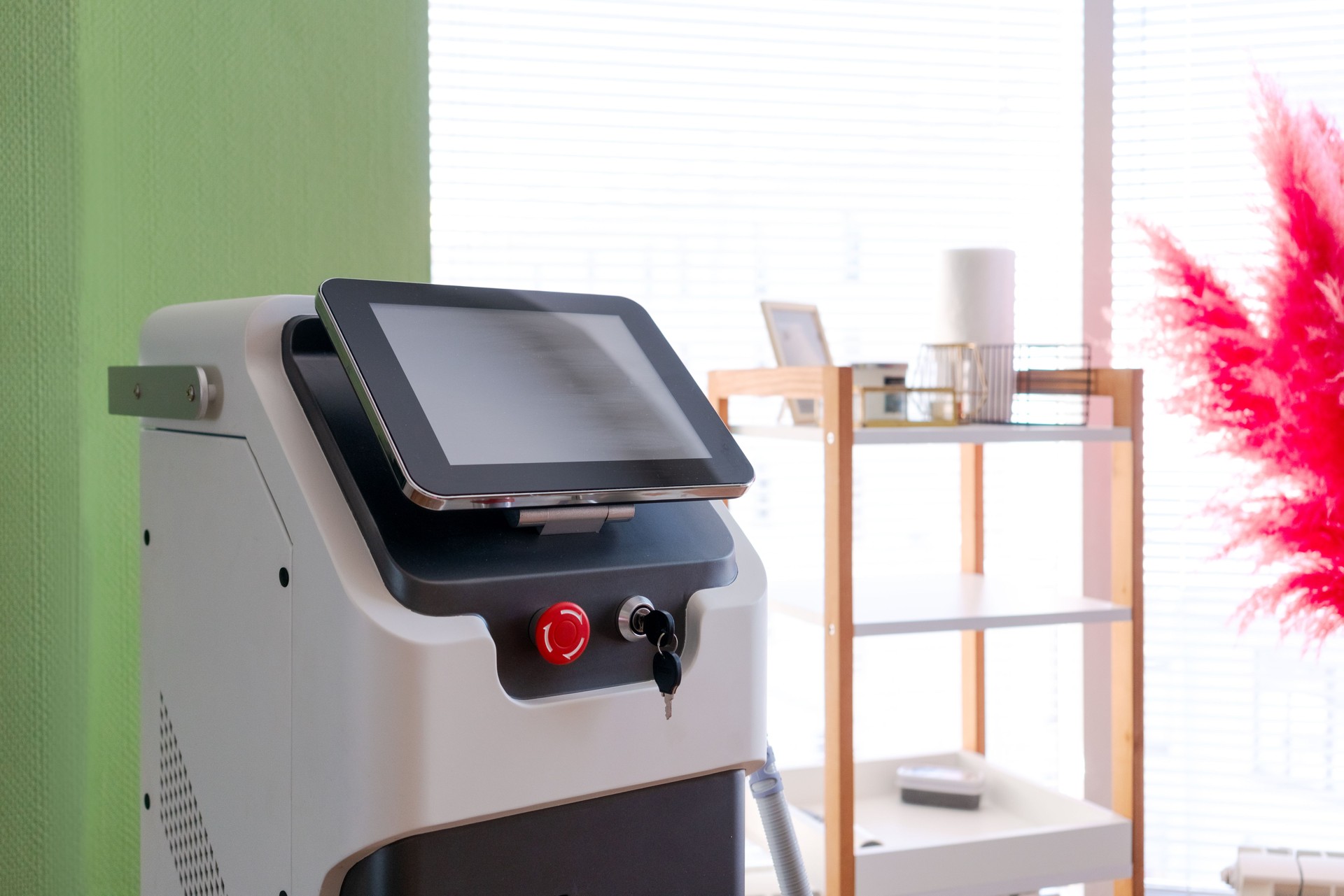 A white device with a red button sits on a green wall